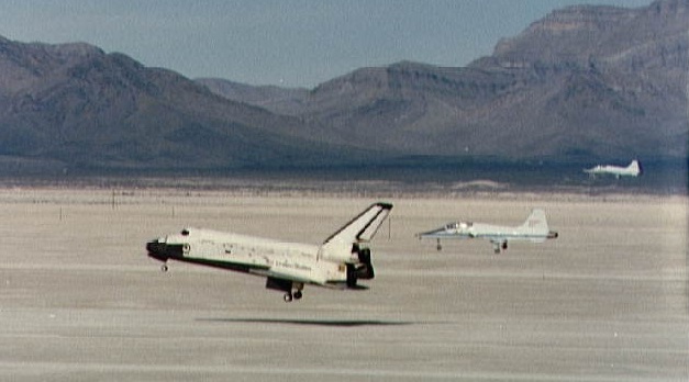 Space Shuttle Columbia is shown seconds from touchdown with two T-38 chase planes following it in to the landing strip, following the completion of the STS-3 mission.